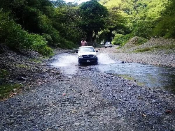 98979727-d5bf-433d-a1fa-9d678623cef4 4x4 off-road vehicle driving through shallow river on Tobago rainforest tour.